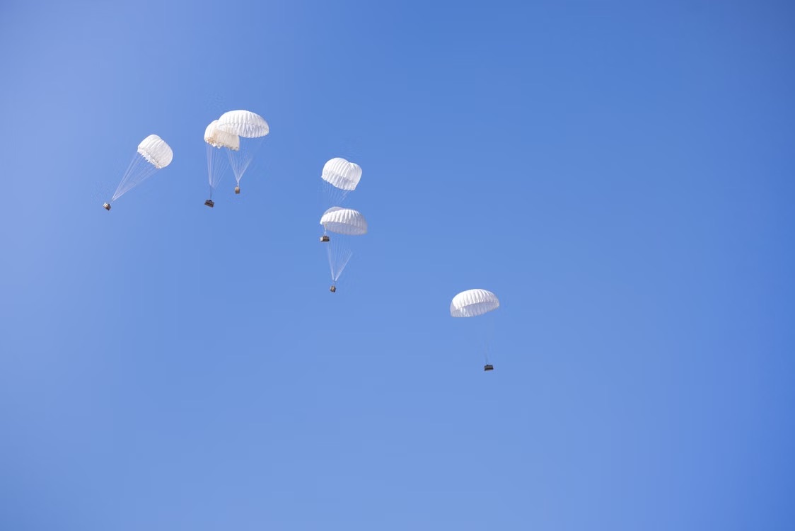 Supplies delivered by parachute against a clear sky